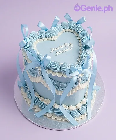 Light blue heart-shaped cake with soft icing, piped borders, and blue satin ribbon bows Light blue heart-shaped cake with soft icing, piped borders, and blue satin ribbon bows