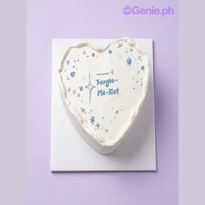 White heart-shaped cake with blue piped icing stars and text White heart-shaped cake with blue piped icing stars and text