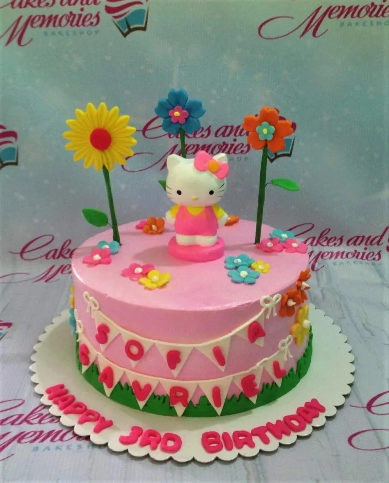 A pink 1-tier Hello Kitty cake with a Hello Kitty figure, colorful fondant flowers, and a personalized name banner. A pink 1-tier Hello Kitty cake with a Hello Kitty figure, colorful fondant flowers, and a personalized name banner.