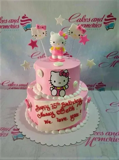 A pink two-tier cake themed around Hello Kitty, featuring fondant figures, stars, and a white plaque with a message. A pink two-tier cake themed around Hello Kitty, featuring fondant figures, stars, and a white plaque with a message.