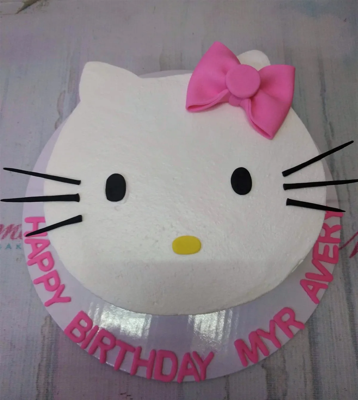 A white 1 Tier Hello Kitty face cake with a pink fondant bow, black fondant eyes and whiskers, and a yellow nose. A white 1 Tier Hello Kitty face cake with a pink fondant bow, black fondant eyes and whiskers, and a yellow nose.