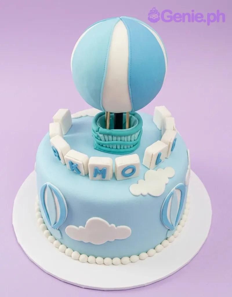 A blue and white 1-tier fondant cake, Hot Air Balloon themed, with a striped balloon topper and white fondant clouds. A blue and white 1-tier fondant cake, Hot Air Balloon themed, with a striped balloon topper and white fondant clouds.