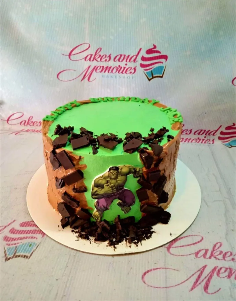 Hulk themed birthday cake with green icing, chocolate shards, and a Hulk character printout on the side. Hulk themed birthday cake with green icing, chocolate shards, and a Hulk character printout on the side.