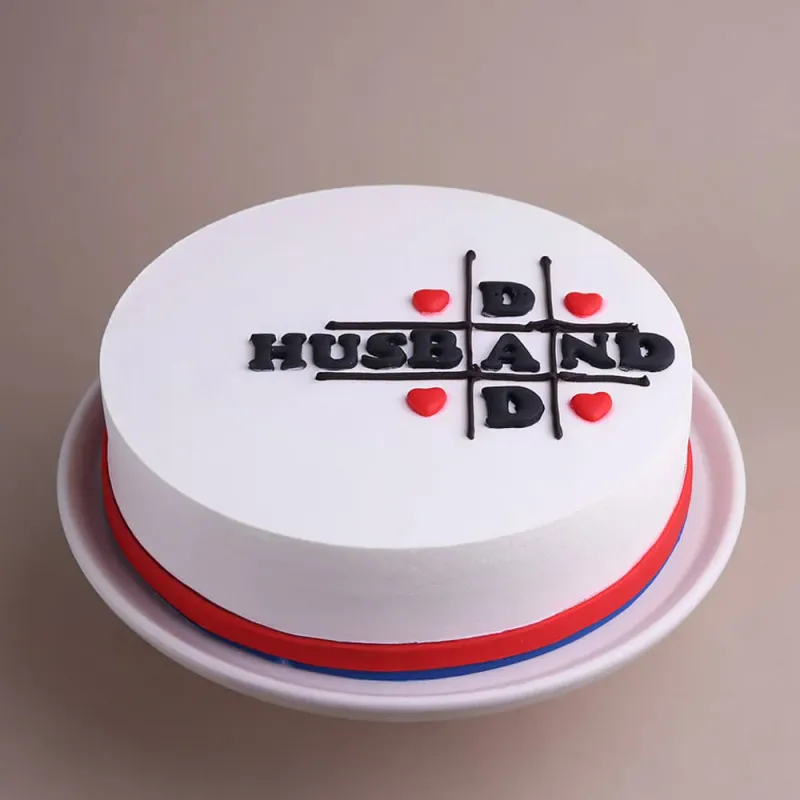 White minimalist cake with a black tic-tac-toe design spelling HUSBAND and DAD with red heart accents. White minimalist cake with a black tic-tac-toe design spelling HUSBAND and DAD with red heart accents.