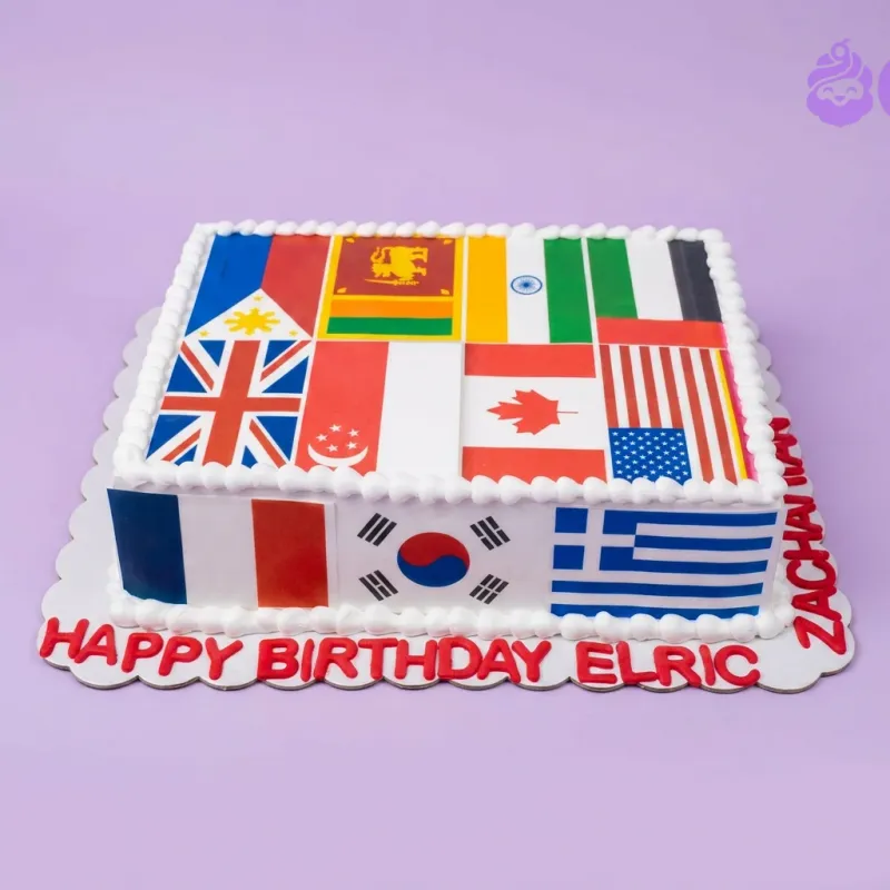 A white square cake themed around International Flags, featuring various national flags, piped white borders, and a red text message. A white square cake themed around International Flags, featuring various national flags, piped white borders, and a red text message.