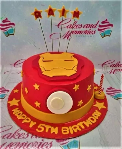 Red and yellow Iron Man themed birthday cake with a fondant mask on top and star decorations. Red and yellow Iron Man themed birthday cake with a fondant mask on top and star decorations.