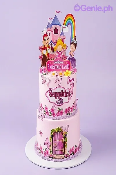 A pink 2-tier cake themed around Jollibee Fairytale Land, featuring character printouts, a pink castle, and a rainbow. A pink 2-tier cake themed around Jollibee Fairytale Land, featuring character printouts, a pink castle, and a rainbow.