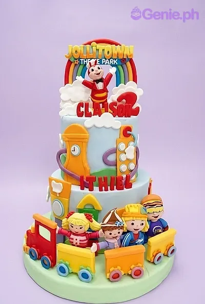 A light blue three-tier fondant cake themed around Jollitown, featuring Jollibee, Jollitown characters, a train, rainbow, and clouds. A light blue three-tier fondant cake themed around Jollitown, featuring Jollibee, Jollitown characters, a train, rainbow, and clouds.