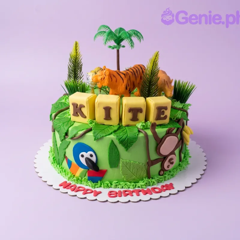 A green 1 Tier cake themed around Jungle Safari, featuring tiger, rhino, and leopard figures, plus 'KITE' blocks and palm trees. A green 1 Tier cake themed around Jungle Safari, featuring tiger, rhino, and leopard figures, plus 'KITE' blocks and palm trees.