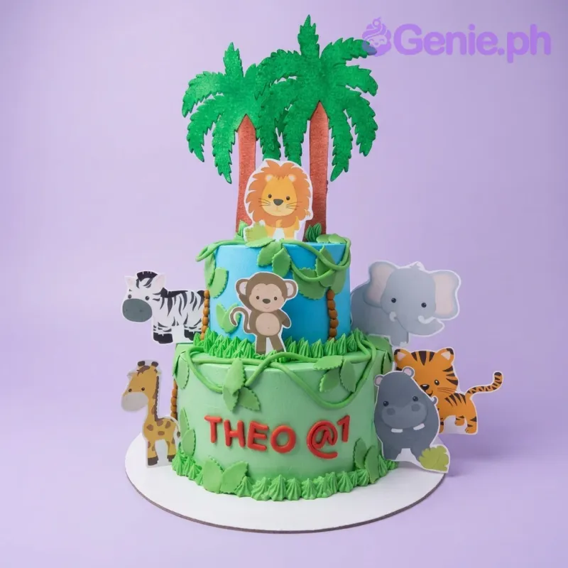 A green and blue 2 Tier cake themed around Jungle Safari, featuring printout animal toppers and jungle foliage accents. A green and blue 2 Tier cake themed around Jungle Safari, featuring printout animal toppers and jungle foliage accents.
