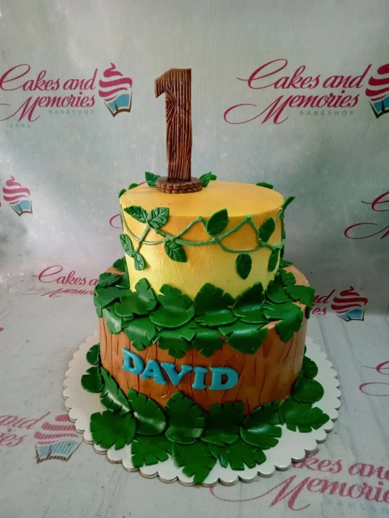 A multicolor 2 Tier Fondant Jungle Safari cake, with a '1' topper and green leaves. A multicolor 2 Tier Fondant Jungle Safari cake, with a '1' topper and green leaves.