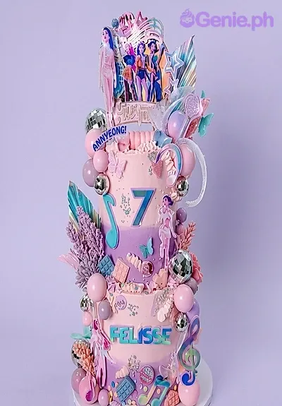 A pink and purple 3-tier cake themed around K-Pop, featuring character printouts and disco balls, musical notes, purple foliage, and teal butterflies. A pink and purple 3-tier cake themed around K-Pop, featuring character printouts and disco balls, musical notes, purple foliage, and teal butterflies.