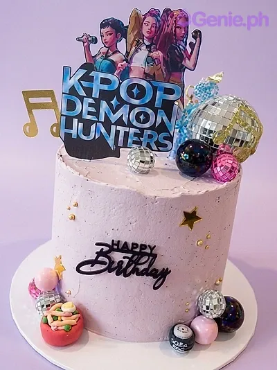 A white 1-tier cake themed around K-pop Demon Hunters, featuring character printouts, disco balls, and gold stars. A white 1-tier cake themed around K-pop Demon Hunters, featuring character printouts, disco balls, and gold stars.