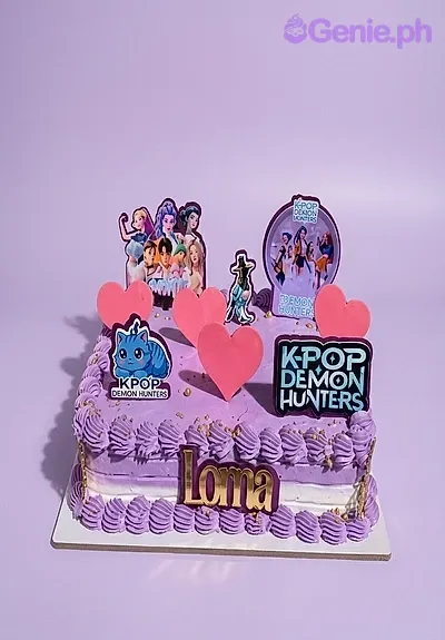 A purple rectangle K-Pop Demon Hunters cake, featuring character and logo printouts, pink hearts, and purple rosettes. A purple rectangle K-Pop Demon Hunters cake, featuring character and logo printouts, pink hearts, and purple rosettes.