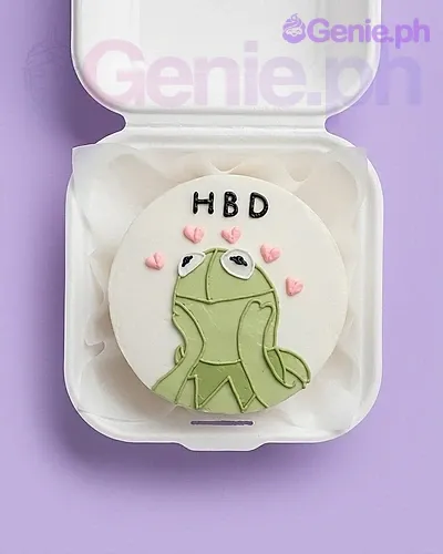 A white bento cake themed around Kermit the Frog, featuring a green Kermit icing illustration, pink hearts, and a black HBD message. A white bento cake themed around Kermit the Frog, featuring a green Kermit icing illustration, pink hearts, and a black HBD message.