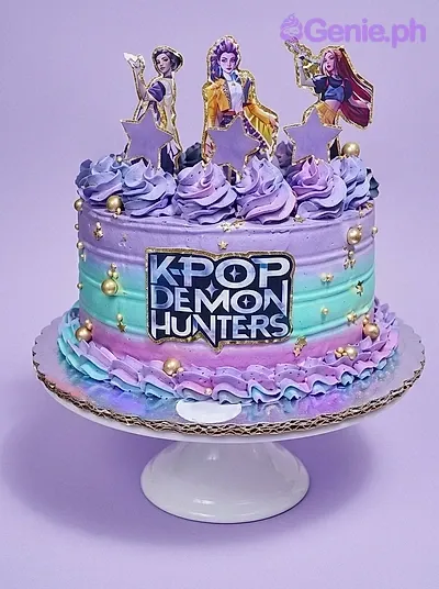 A purple and teal gradient 1-Tier cake themed around Kpop Demon Hunters, featuring character and star printouts, purple icing swirls, and gold dragees. A purple and teal gradient 1-Tier cake themed around Kpop Demon Hunters, featuring character and star printouts, purple icing swirls, and gold dragees.