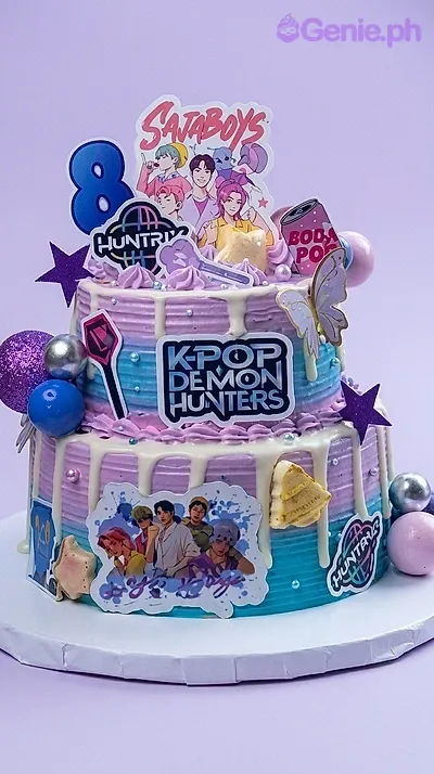 Two-tier K-pop Demon Hunters themed cake with purple and blue gradient icing, white drips, and various character printouts. Two-tier K-pop Demon Hunters themed cake with purple and blue gradient icing, white drips, and various character printouts.