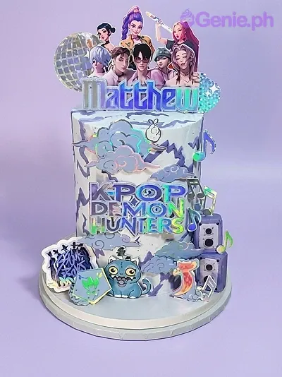 A white 1-tier Kpop Demon Hunters cake, featuring K-pop idol characters, a holographic disco ball, blue monster, and speakers. A white 1-tier Kpop Demon Hunters cake, featuring K-pop idol characters, a holographic disco ball, blue monster, and speakers.