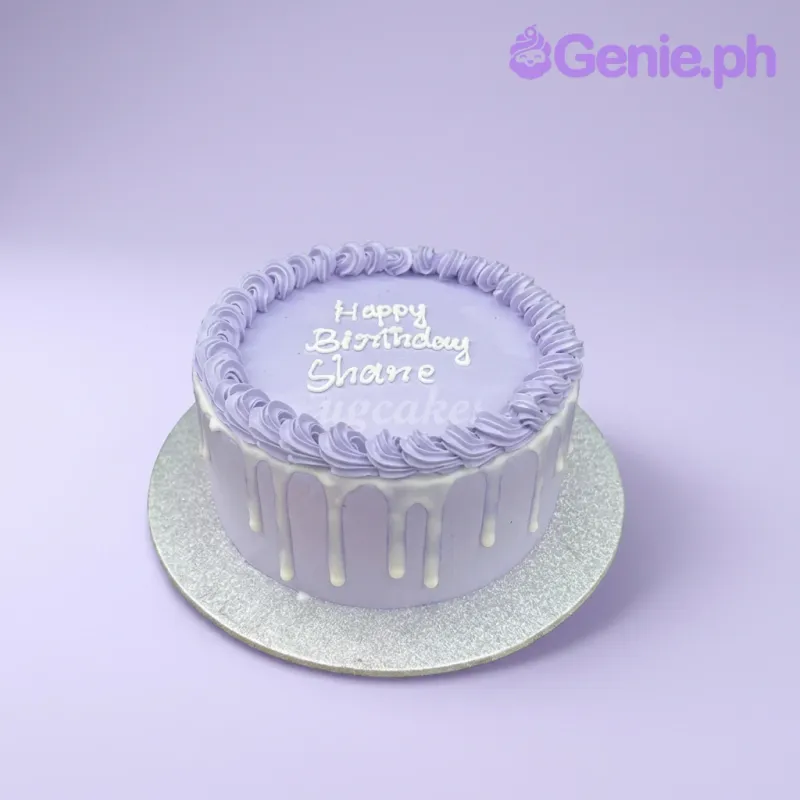 A lavender purple and white 1-tier cake with a minimalist design, featuring a white icing drip, piped border, and 'Happy Birthday Shane' text. A lavender purple and white 1-tier cake with a minimalist design, featuring a white icing drip, piped border, and 'Happy Birthday Shane' text.