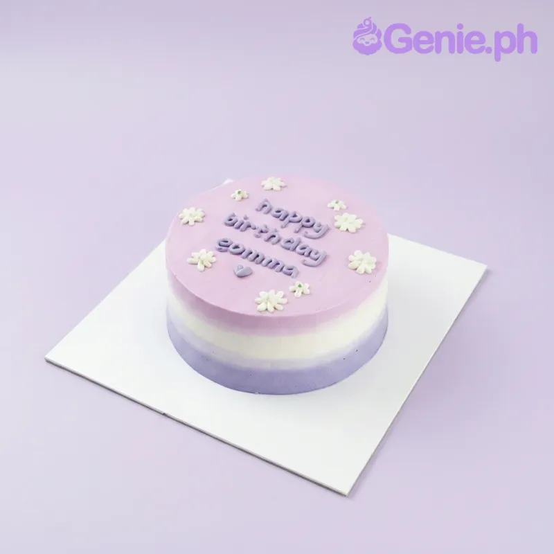 A lavender, blue, white, and purple 1-tier cake themed around Minimalist Lavender, featuring white icing flowers and a purple piped message. A lavender, blue, white, and purple 1-tier cake themed around Minimalist Lavender, featuring white icing flowers and a purple piped message.