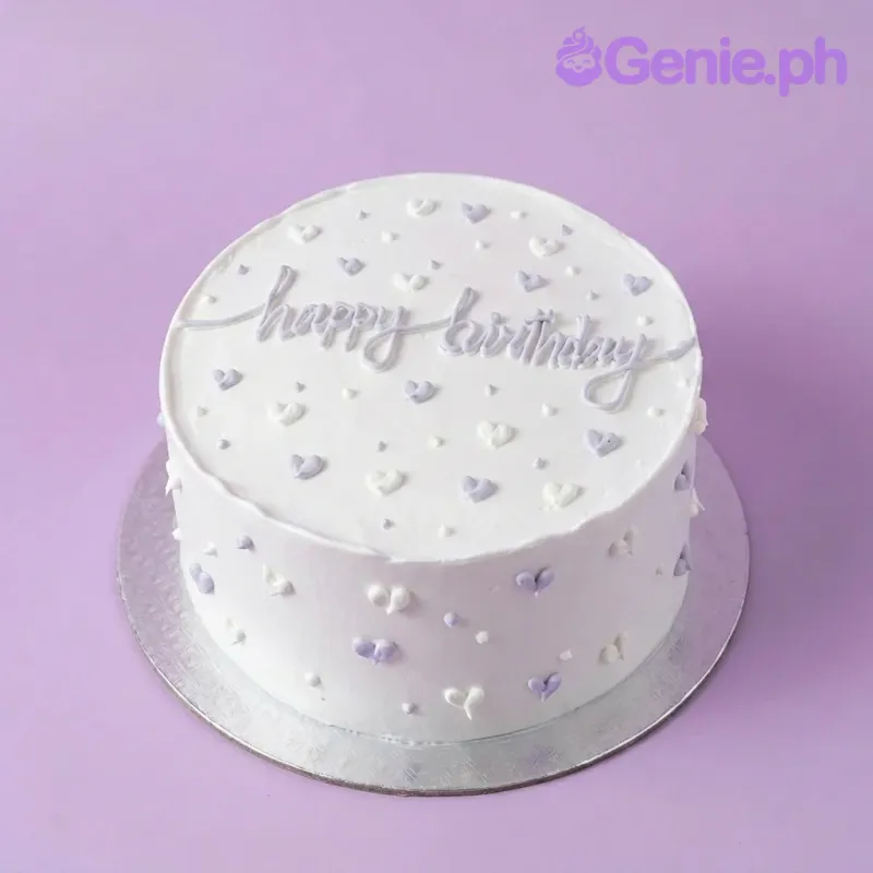 A white and lavender 1 Tier Lavender Minimalist cake, featuring piped hearts and a cursive "Happy Birthday" message. A white and lavender 1 Tier Lavender Minimalist cake, featuring piped hearts and a cursive "Happy Birthday" message.