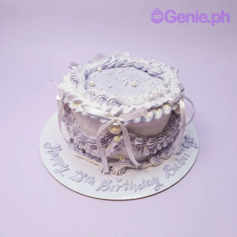 Lavender and white 1-tier vintage cake with soft icing, piped borders, white ribbon bows, and pearl sprinkles