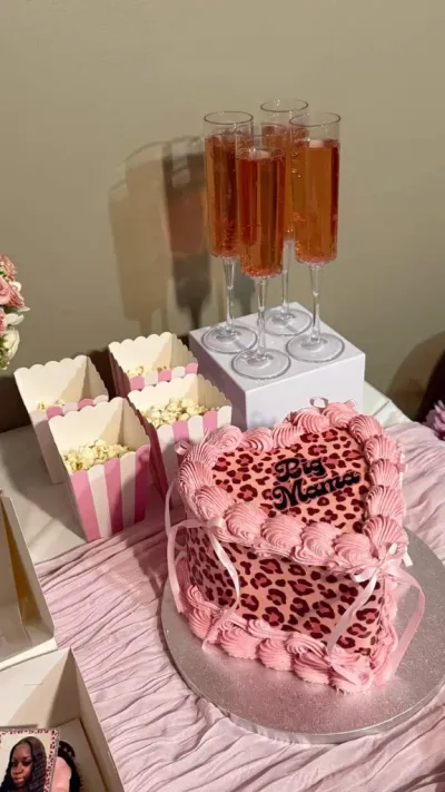 Pink heart-shaped cake with smooth soft icing, leopard print side panel wrap, and a black lettering sign printout Pink heart-shaped cake with smooth soft icing, leopard print side panel wrap, and a black lettering sign printout