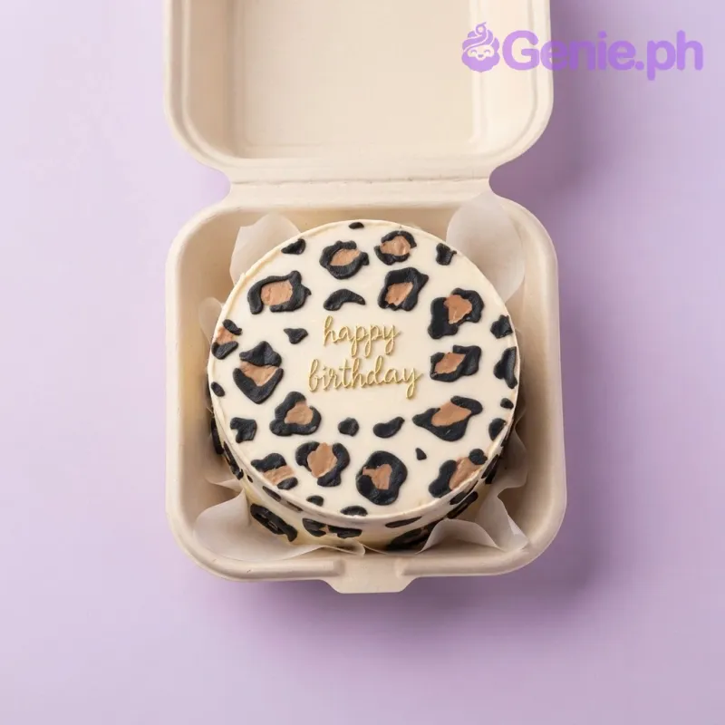Beige bento cake with soft icing, brown and black piped leopard print, and a gold piped birthday message Beige bento cake with soft icing, brown and black piped leopard print, and a gold piped birthday message