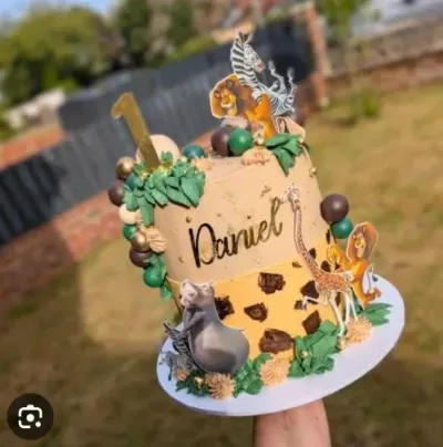 Ivory two-tier safari birthday cake with soft icing, Lion King character printouts, and animal figurines Ivory two-tier safari birthday cake with soft icing, Lion King character printouts, and animal figurines