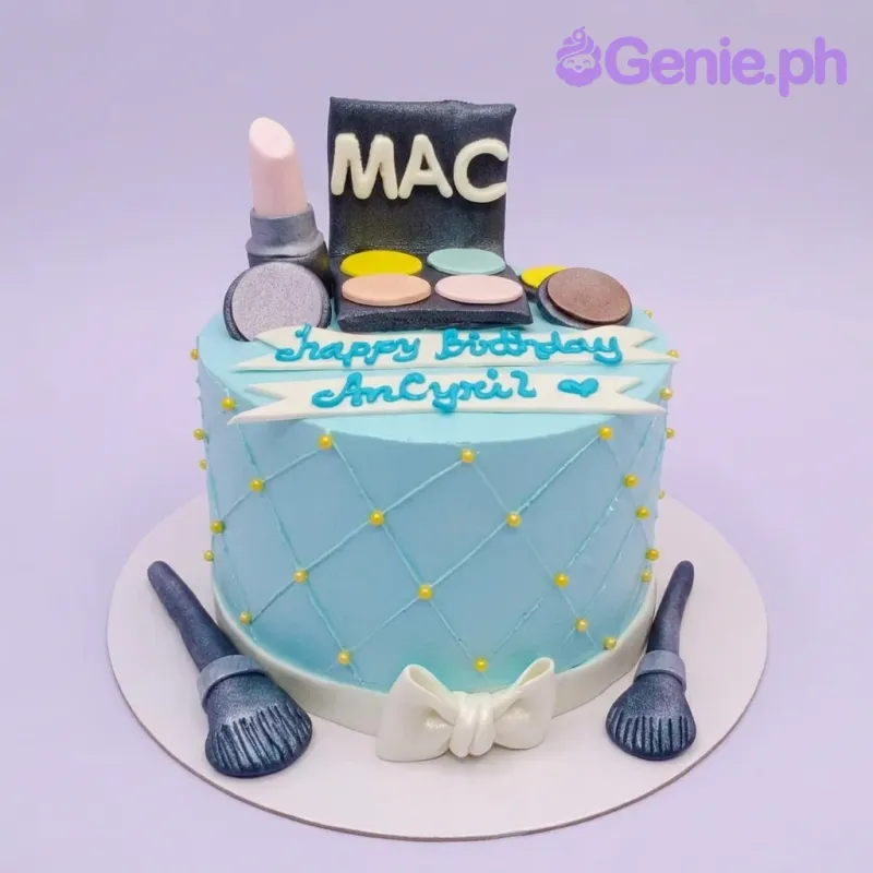 A light blue 1-tier cake themed around MAC Makeup, featuring fondant eyeshadow palette, lipstick, and brushes with yellow pearl accents. A light blue 1-tier cake themed around MAC Makeup, featuring fondant eyeshadow palette, lipstick, and brushes with yellow pearl accents.