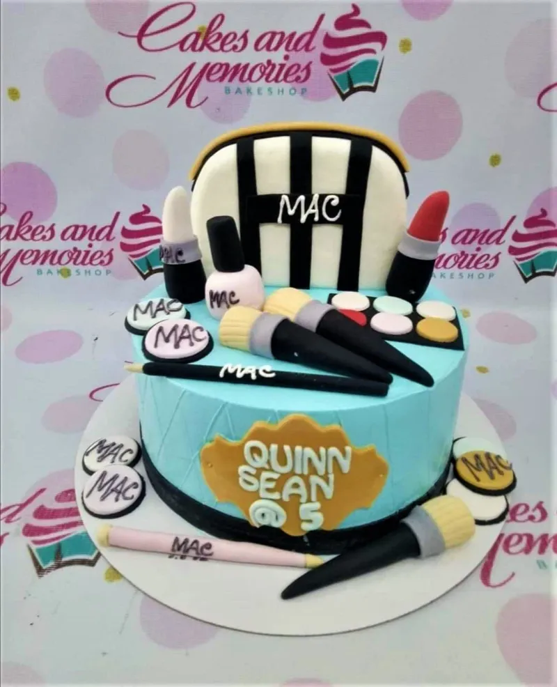 A light blue 1 Tier Fondant cake themed around MAC Makeup, featuring various cosmetic items and a personalized message. A light blue 1 Tier Fondant cake themed around MAC Makeup, featuring various cosmetic items and a personalized message.
