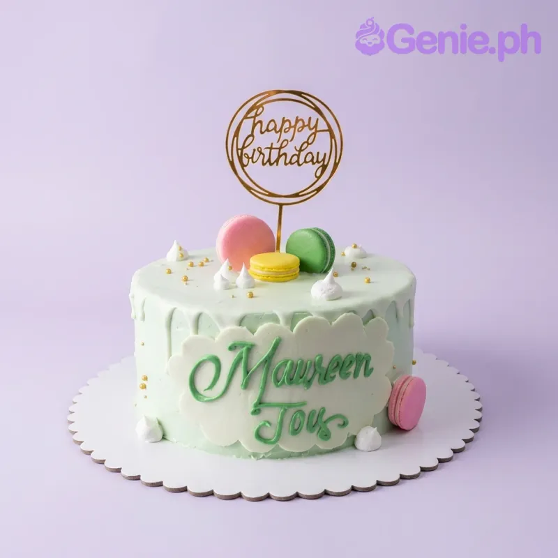 A light green 1-tier Macaron Birthday cake, featuring a gold Happy Birthday topper, colorful macarons, white icing dollops, and a name plaque. A light green 1-tier Macaron Birthday cake, featuring a gold Happy Birthday topper, colorful macarons, white icing dollops, and a name plaque.