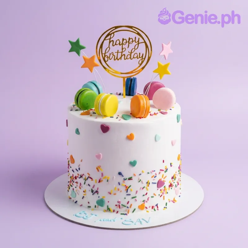 A white 1-tier cake themed Macaron Birthday, featuring a gold "Happy Birthday" topper, macarons, and fondant stars. A white 1-tier cake themed Macaron Birthday, featuring a gold "Happy Birthday" topper, macarons, and fondant stars.