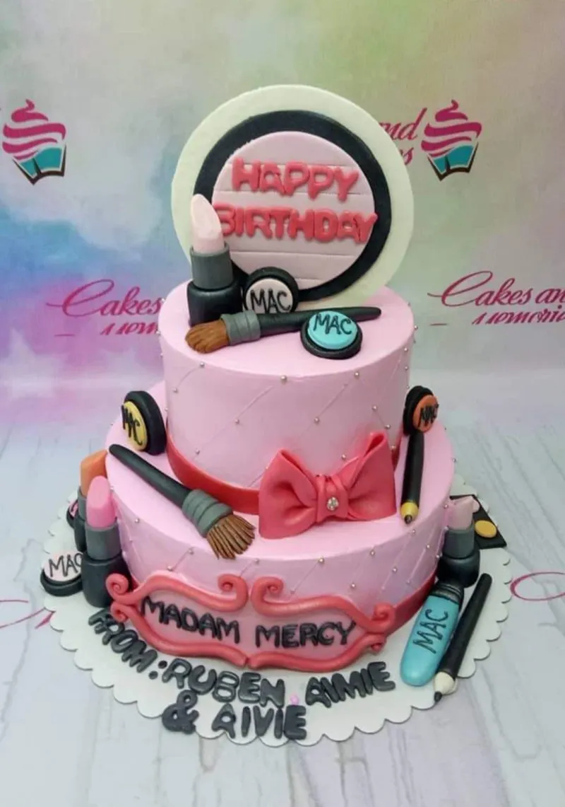 A pink and white 2-tier fondant cake themed around Makeup Birthday, featuring a large makeup compact, a pink bow, lipsticks, and brushes. A pink and white 2-tier fondant cake themed around Makeup Birthday, featuring a large makeup compact, a pink bow, lipsticks, and brushes.