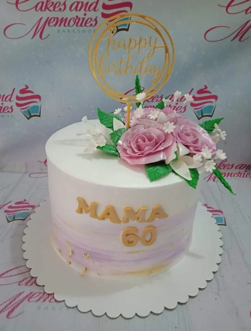 A white and lavender 1-tier birthday cake themed around Mama's 60th birthday, featuring a gold 'Happy Birthday' topper, pink edible roses, and 'MAMA 60' in gold lettering. A white and lavender 1-tier birthday cake themed around Mama's 60th birthday, featuring a gold 'Happy Birthday' topper, pink edible roses, and 'MAMA 60' in gold lettering.
