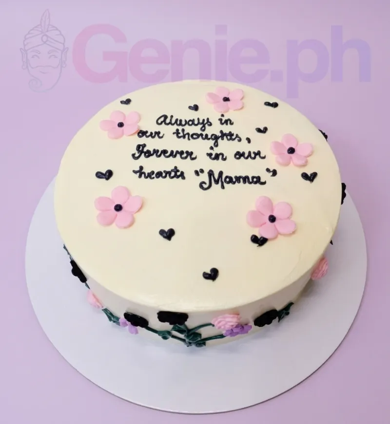 A white round 1-tier cake themed for Mama, with pink fondant flowers, black piped text, and a floral icing vine. A white round 1-tier cake themed for Mama, with pink fondant flowers, black piped text, and a floral icing vine.