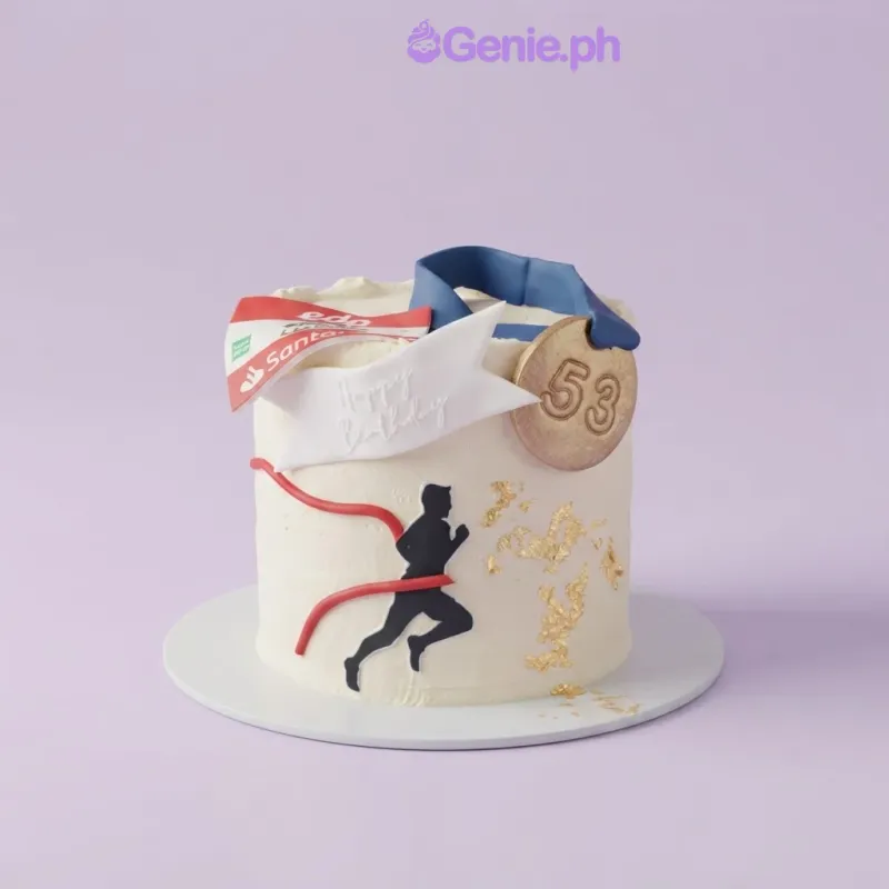 White 1-tier cake with a runner silhouette, a gold medal topper with number 53, and a printed race bib. White 1-tier cake with a runner silhouette, a gold medal topper with number 53, and a printed race bib.