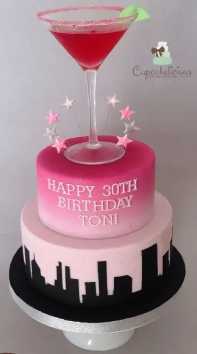 Hot pink and light pink 2-tier fondant birthday cake with an edible martini glass topper, star candles, and a black cityscape silhouette panel Hot pink and light pink 2-tier fondant birthday cake with an edible martini glass topper, star candles, and a black cityscape silhouette panel