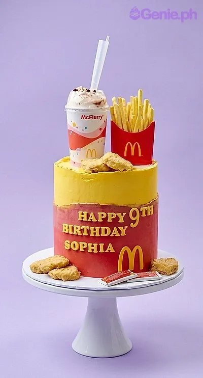 A yellow and red 1-tier cake themed around McDonald's, featuring a milkshake cup, french fries, and chicken nuggets. A yellow and red 1-tier cake themed around McDonald's, featuring a milkshake cup, french fries, and chicken nuggets.