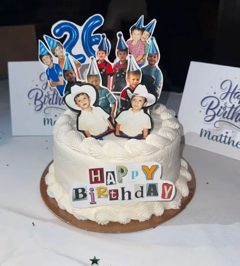 White 1 tier cake with smooth soft icing, photo cutouts of a boy wearing party hats, and a blue number topper White 1 tier cake with smooth soft icing, photo cutouts of a boy wearing party hats, and a blue number topper
