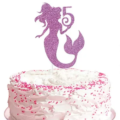 A white 1 Tier cake themed around Mermaid, featuring a large purple glitter mermaid silhouette with the number five and pink sprinkles. A white 1 Tier cake themed around Mermaid, featuring a large purple glitter mermaid silhouette with the number five and pink sprinkles.