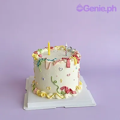 White single-tier birthday cake with colorful piped icing squiggles and two candles on top White single-tier birthday cake with colorful piped icing squiggles and two candles on top