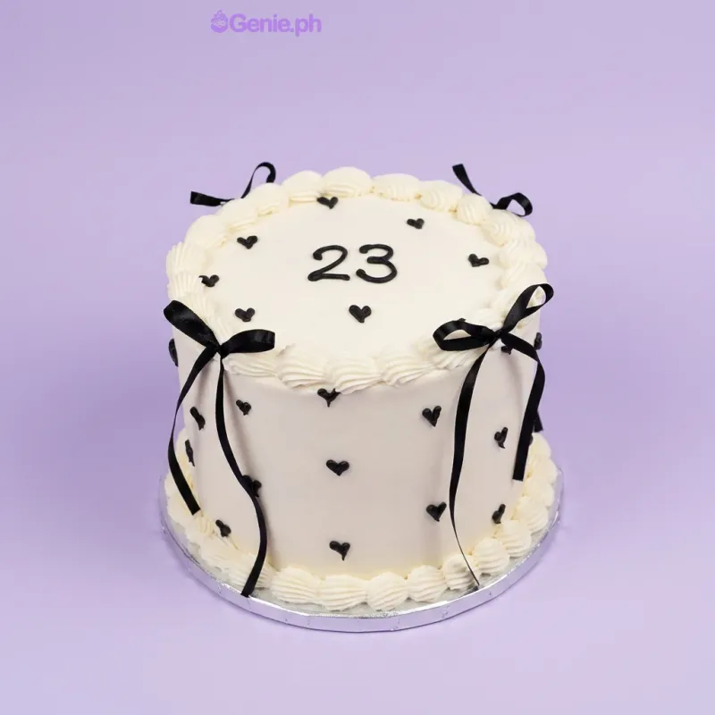 White single-tier cake with black piped hearts and black satin ribbon bows White single-tier cake with black piped hearts and black satin ribbon bows
