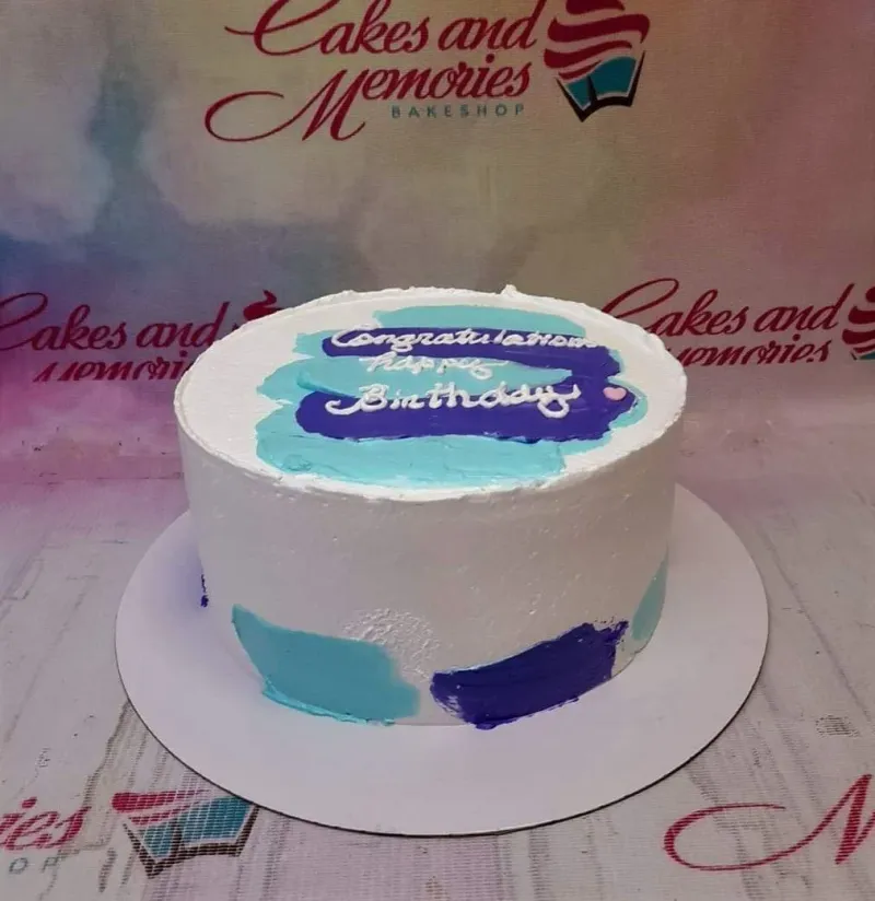 A white 1 Tier minimalist palette knife cake, featuring teal and purple icing strokes and a 'Congratulations Happy Birthday' message. A white 1 Tier minimalist palette knife cake, featuring teal and purple icing strokes and a 'Congratulations Happy Birthday' message.