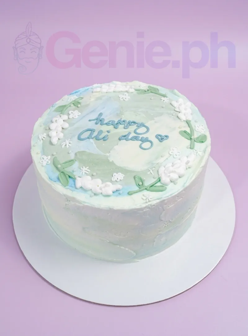 A white bento-style Minimalist cake with blue and green palette knife icing, white piped flowers, and 'happy Ali day' message. A white bento-style Minimalist cake with blue and green palette knife icing, white piped flowers, and 'happy Ali day' message.