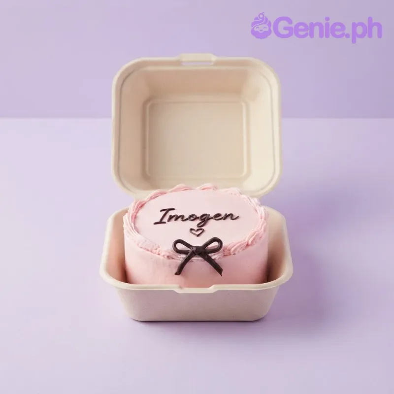 Pink bento cake with soft icing, black piped script reading Imogen, a small heart, and a black fondant bow Pink bento cake with soft icing, black piped script reading Imogen, a small heart, and a black fondant bow