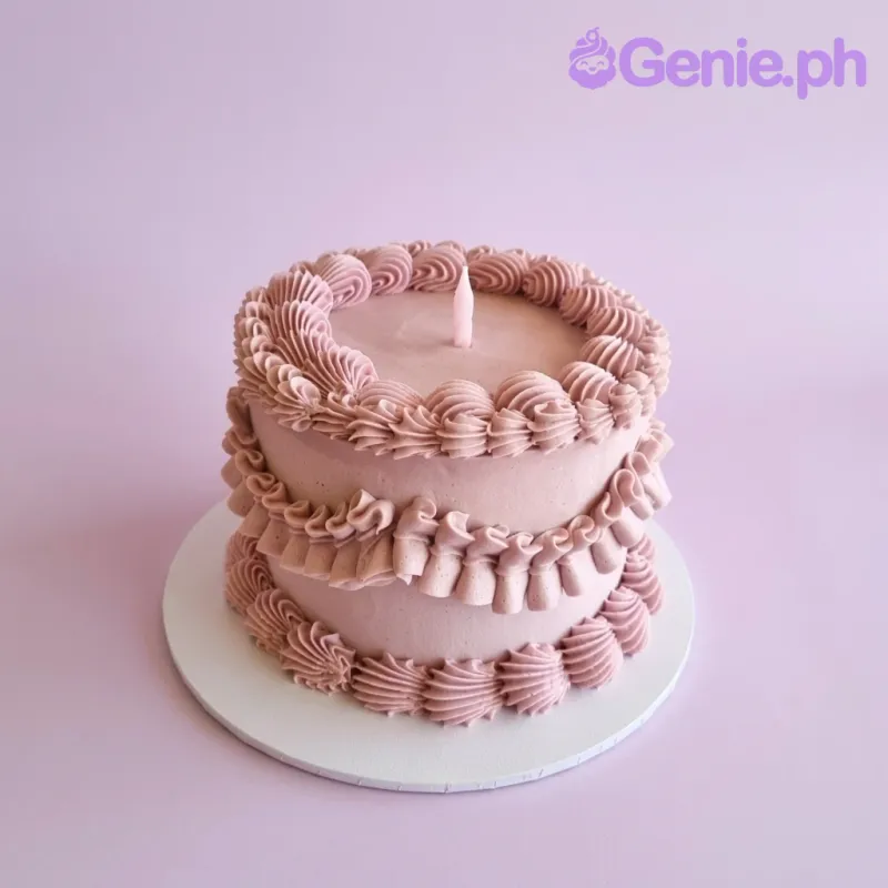 Light pink 1-tier cake with piped icing ruffles and a single pink candle Light pink 1-tier cake with piped icing ruffles and a single pink candle