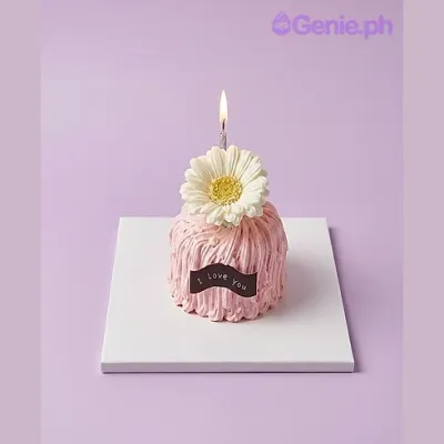 Pink 1-tier cake with white flower, lit candle, and I love you banner Pink 1-tier cake with white flower, lit candle, and I love you banner