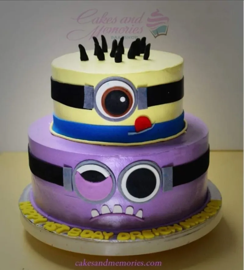 A yellow and purple two-tier fondant Minion cake featuring a one-eyed Minion and an Evil Minion. A yellow and purple two-tier fondant Minion cake featuring a one-eyed Minion and an Evil Minion.