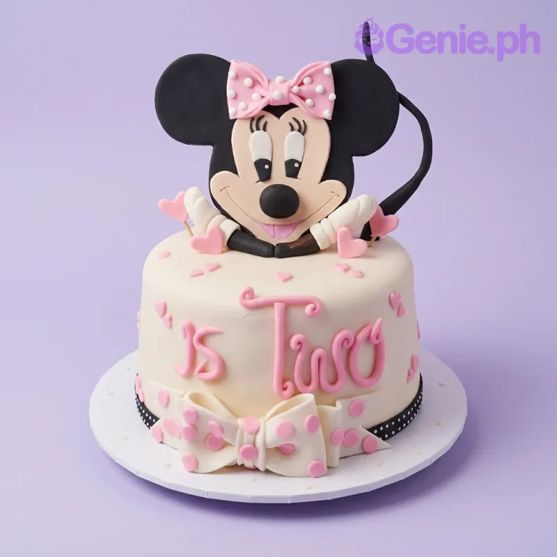 A white and pink 1 Tier Fondant cake themed around Minnie Mouse, featuring a large Minnie Mouse topper, pink fondant hearts, and a polka dot bow. A white and pink 1 Tier Fondant cake themed around Minnie Mouse, featuring a large Minnie Mouse topper, pink fondant hearts, and a polka dot bow.